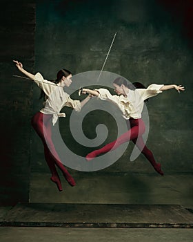 Two young female ballet dancers like duelists with swords. Ballet and contemporary choreography concept. Creative art