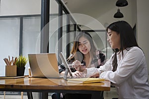 Two young female designer using computer tablet and discussing their project .