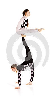 Two young female equilibrists perform acrobatic elements on a white background
