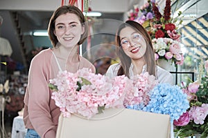 Two Young female florists\' partner delivers a floral bunch with a happy smile.