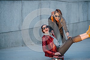 Two young female friends having fun with skateboard together