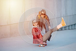 Two young female friends having fun with skateboard together