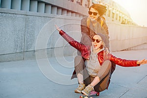 Two young female friends having fun with skateboard together