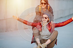 Two young female friends having fun with skateboard together