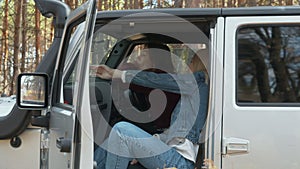 Two young female friends sits in a white car jeep in autumn forest