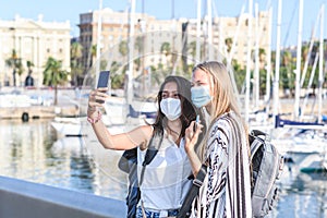 Two young female tourists taking a self picture in leisure port during Covid19 pandemic