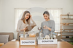 Two young female volunteers help pack food into donation boxes and prepare donation boxes to take to charities. photo