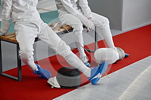 Two young fencers talking while sitting on bench after training