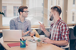 Two young freelancers working online on project plans best friends talking having conversation in cafe looking at each other gestu photo