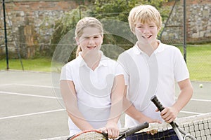 Two young friends on tennis court smiling