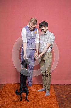 Two young gay man playing with a puppy