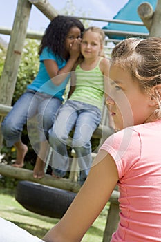 Two young girl friends at a playground whispering