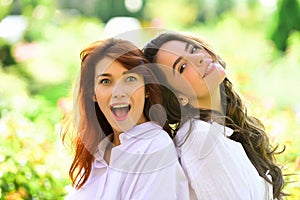 Two young girl friends together on walk. Portrait of beautiful young women looking at camera in park.