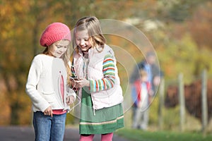 Two Young Girl Listening To MP3 Player Outdoors
