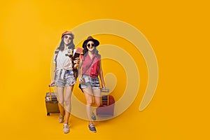 Two young girl traveller holding suitcase in studio.