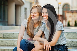 Two girlfriends sitting on the stairs and listening music