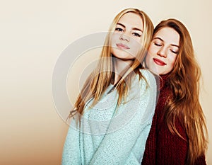 Two young girlfriends in winter sweaters indoors having fun. Lif