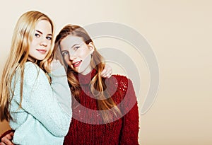 Two young girlfriends in winter sweaters indoors having fun. Lif