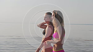 Two young girls in bikinis on the beach walk