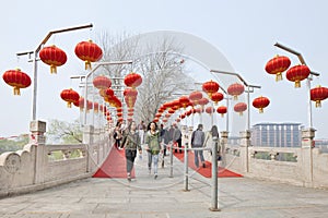 Two young girls on a bridge with red lanterns, Beijing, China.
