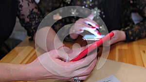 Two young girls browse internet using smart phone wireless online in cafe. Hands holding device closeup.