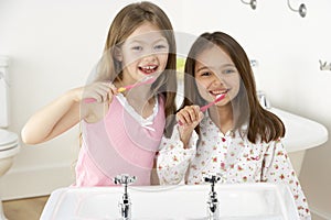 Two Young Girls Brushing Teeth at Sink