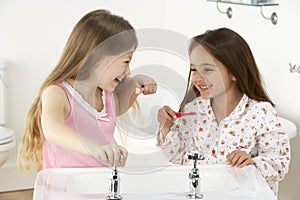 Two Young Girls Brushing Teeth at Sink