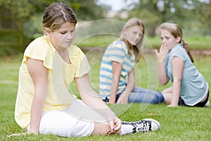 Two young girls bullying other young girl outdoors