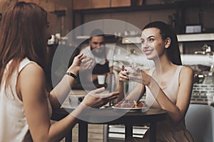 Two young girls communicate in a cafe at the table