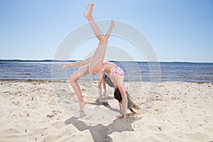 Young girls doing gymnastic and cartwheel on the beach