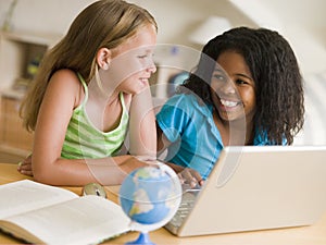 Two Young Girls Doing Their Homework On A Laptop