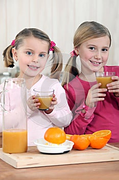 Two young girls drinking juice