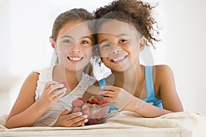 Two young girls eating strawberries