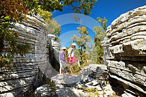 Two young girls exploring Stone forest, natural rock formation, created by multiple layers of stone, located near Monodendri