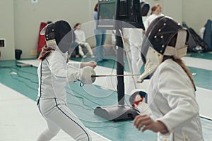 Two young girls fencers having fencing duel on tournament