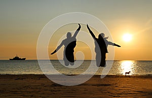 Two young girls jumping at beach