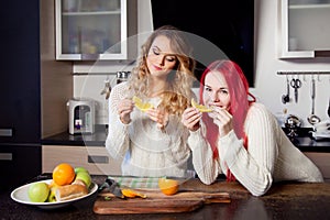 Two young girls in the kitchen talking and eating