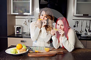Two young girls in the kitchen talking and eating