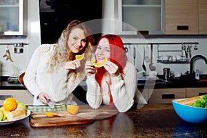 Two young girls in the kitchen talking and eating fruit, healthy lifestyle