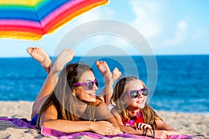 Two young girls laying together on beach.