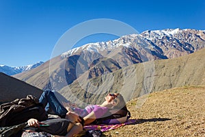 Two young girls lying on arid ground by Andes snowy mountain range