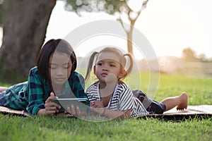 Two young girls lying on the lawn looking at their phones, summer, golden hour, sunset. SSTKHome