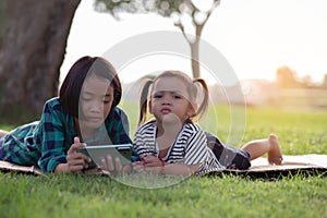 Two young girls lying on the lawn looking at their phones, summer, golden hour, sunset. SSTKHome