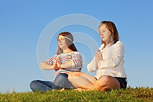 Two young girls meditate and reflect at grass