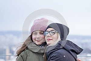 Two young girls are photographed on the observation deck on the background of the old city at a bird`s-eye view