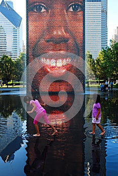 Two young girls play in the waters of the Crown Fountain