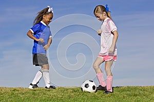 Two young girls playing soccer