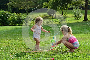 Two young girls playing with toy sprinkler