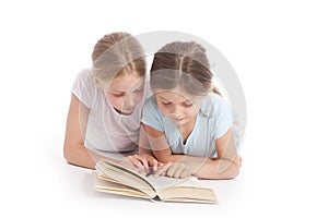 Two young girls reading a book together