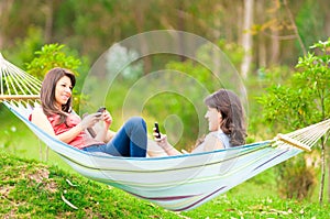 Two young girls resting on a hammock smiling